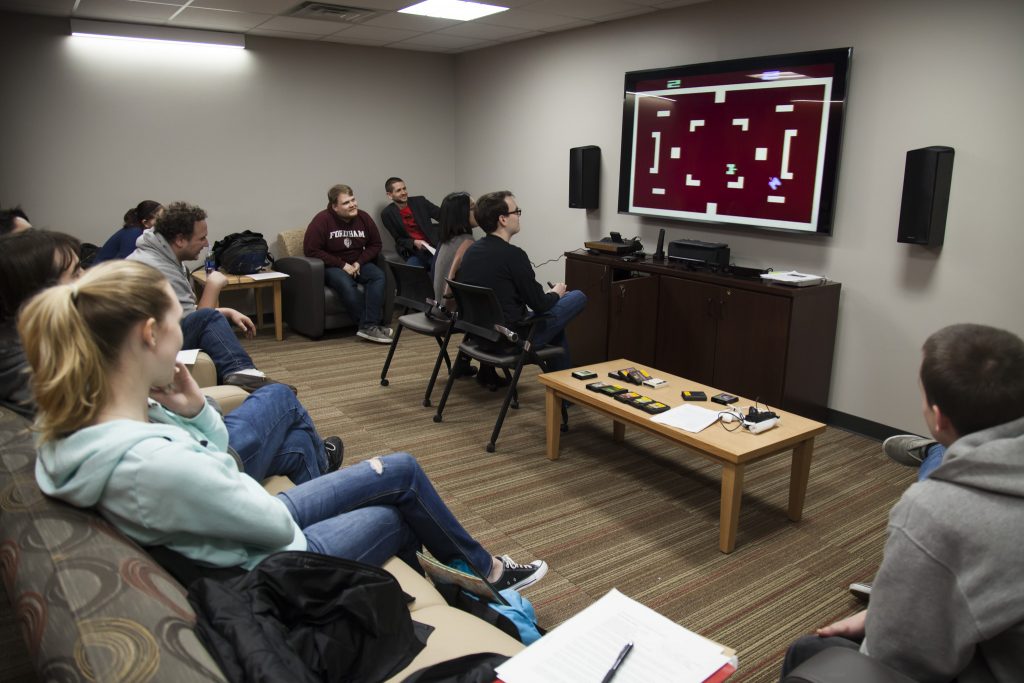 Students in the Living Room Lab look on intensely as two classmates go head-to-head in an Atari video game.