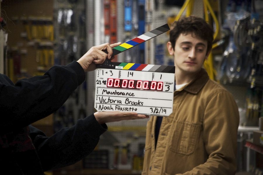 A film slate is held in front of an actor, showing timecode.