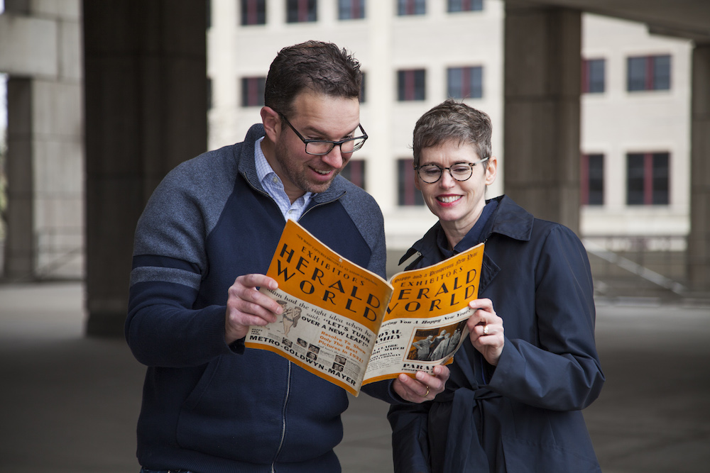 Professors Eric Hoyt and Kelley Conway read an issue of Herald World magazine.