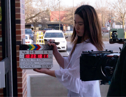 Media Production in Comm Arts - Student Standing with a Timecode Slate in Front of a Camera