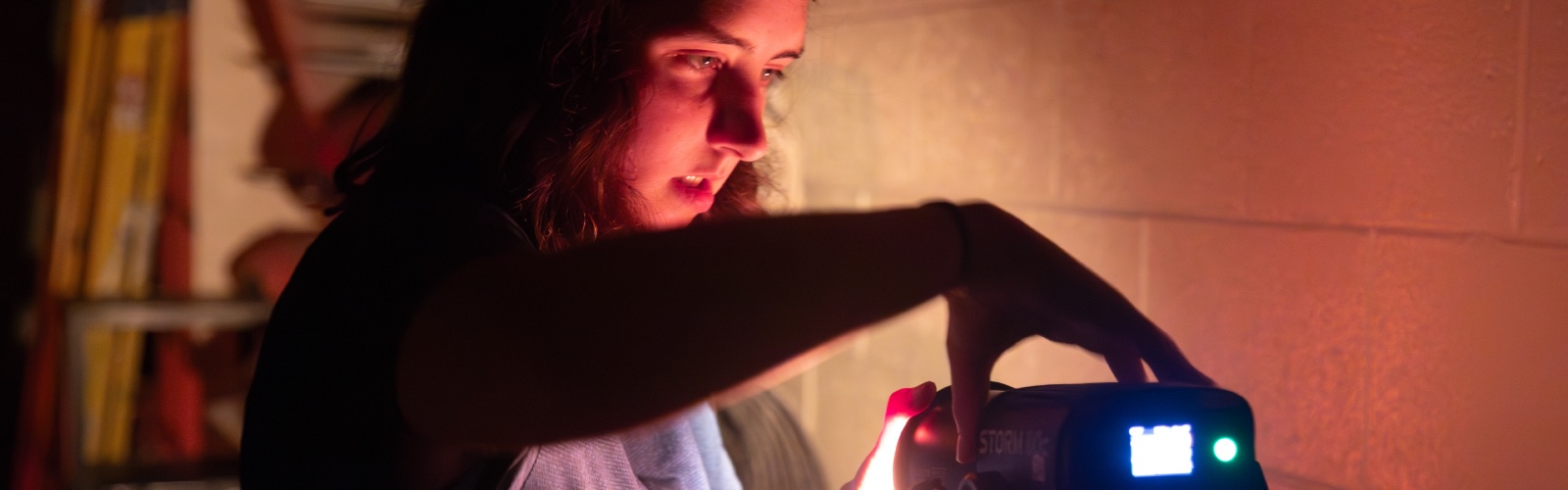 Shannon Finn adjusting a light during a filming session for “CA467 Cinematography and Soundrecording.”